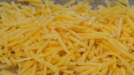 Poster - Grated cheddar cheese falling into a mound on a cutting board