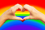 Fototapeta Tęcza - Gay pride concept. Womans hands making heart sign with gay pride LGBT rainbow flag