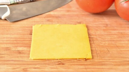 Wall Mural - Slices of cheddar and colby cheese disappearing from a stack on a cutting board, stop motion animation