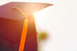 New graduates wear a graduation hat and the orange evening light looks warm.