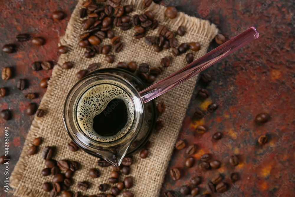 Pot with delicious turkish coffee and beans on grunge background