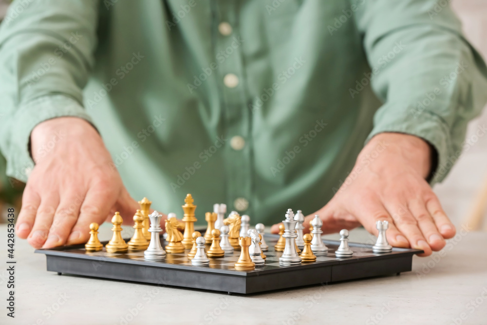 Man playing chess at wooden table, closeup