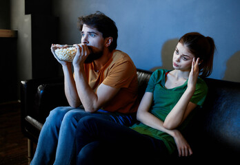 Wall Mural - Young family sitting on the couch watching movies popcorn