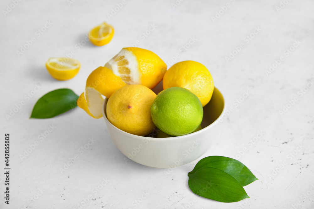 Bowl with healthy citrus fruits on light background