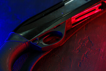 Wall Mural - Hunting shotgun on black background with red and blue backlight