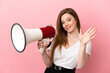 © luismolinero - Teenager girl over isolated pink background holding a megaphone and saluting with hand with happy expression