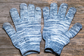 Old dirty household gloves on a wooden background. Close-up. Selective focus.