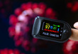 Oximeter in a finger for checking oxygen saturation in blood and heart rate, with blurred Covid-19 illustration