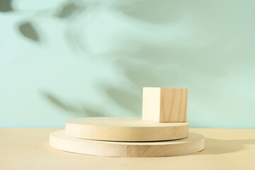 Minimal modern composition with wooden stand for cosmetic products with shadow overlay on neutral blue and beige background.