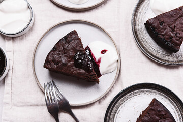 Wall Mural - Slices of rich moist chocolate cherry cake. Homemade dark chocolate sweet brownies cakes with ice cream on greige linen tablecloth. Selective focus