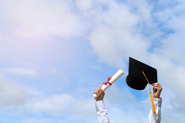 Education. happy students in gowns are celebrating graduation Throwing hands up a certificate and Cap in the air,​Concept of freedom after the struggles they faced throughout the study.