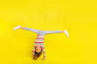 Full body photo of happy young pretty funky girl make handstand good mood isolated on yellow color background
