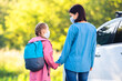 © Ievgen Skrypko - Mother meeting daughter after school during pandemic next to car at sunny day