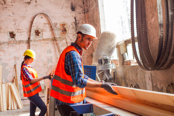 The young workers are cutting boards at the wood factory