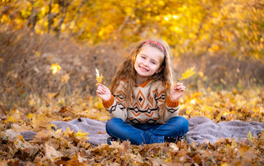 Wall Mural - Cute little girl holding yellow leaves outdoors