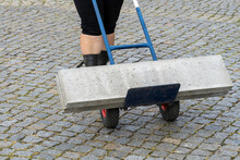 Woman Transporting A Heavy Concrete Block With A Hand Truck Without Protective Work Shoes.