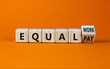 Equal pay and work symbol. Turned the wooden cube and changed words equal pay to equal work. Beautiful orange background. Copy space. Business and equal pay and work concept.