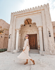 Wall Mural - Woman tourist wearing red turban and biege long dress walks through the old narrow streets of Bur Dubai and Creek. Travel and sightseeing concept