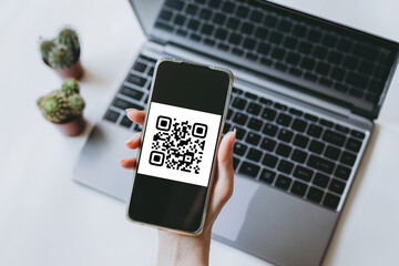 QR code scanning payment and cashless technology concept. Female hand uses a mobile phone to scan a QR code.
