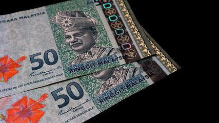 Two pieces of Fifty Ringgit notes, Malaysia's money currency on isolated black backgrounds.