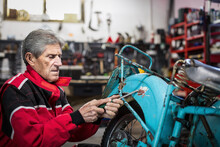 Mechanic Repairing Old Motorcycle In Garage