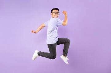 Wall Mural - Portrait of a jumping asian man, isolated on purple background