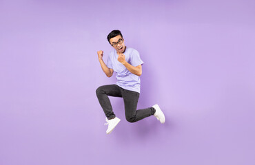 Wall Mural - Portrait of a jumping asian man, isolated on purple background