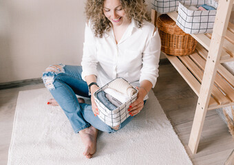 Portrait of a young woman in casual clothes beautifully putting things in containers and boxes. The concept of proper storage of accessories and underwear in the closet