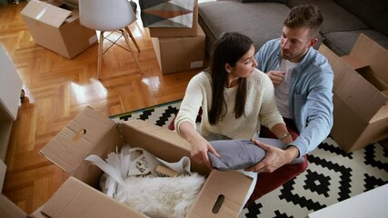 Wall Mural - Smiling couple move into a new home sitting on floor and unpacking.