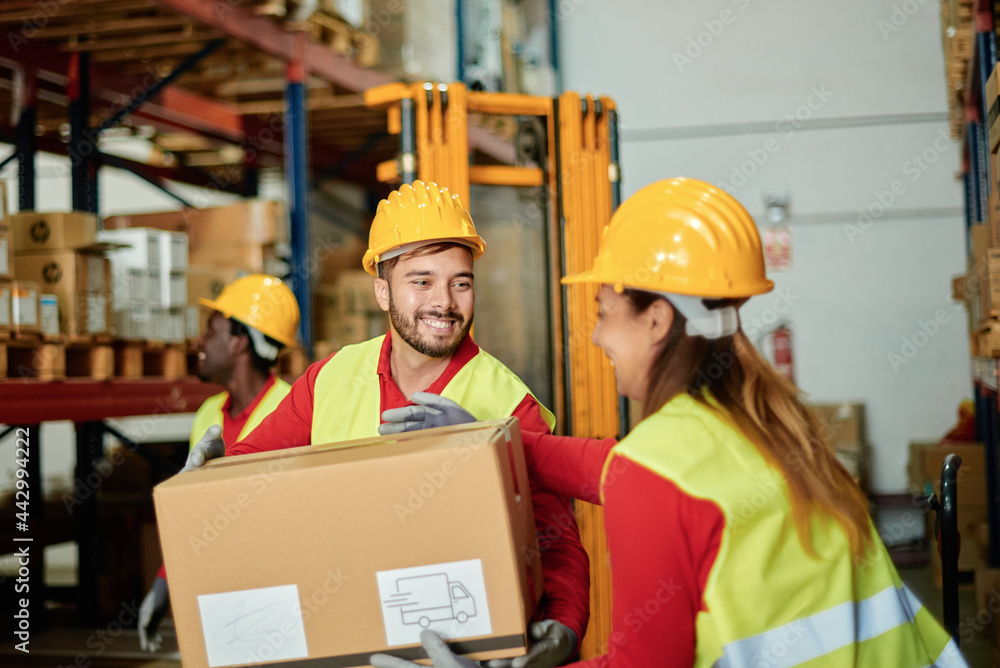 Positive warehouse workers carrying heavy box Stock Photo | Adobe Stock