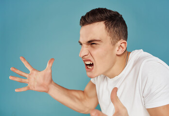 Wall Mural - emotional man in white t-shirt anger blue background