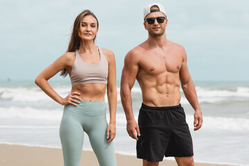 Portraits of Cheerful man and woman athlete standing together at beach