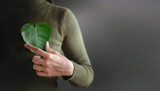 Green Energy, Renewable and Sustainable Resources. Environmental and Ecology Care Concept. Close up of Hand Holding a Heart Shape Green Leaf on Chest