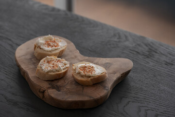 Wall Mural - Baguette slices with cream cheese and herbs on olive wood board