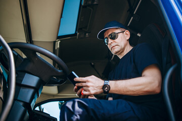 Experienced truck driver sitting in his truck and waiting for a new driving route.