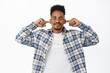 © Cookie Studio - Annoyed young student, african american man cant stand loud music, cover ears with fingers, close eyes and grimacing upset, unwilling to hear bothering noise, white background