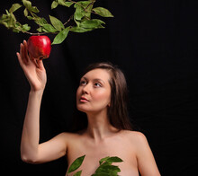 Portrait Of A Young Beautiful Girl In The Image Of A Primitive Woman. The Girl Stretches Out Her Hand And Wants To Pluck An Apple, A Heavenly Fruit.