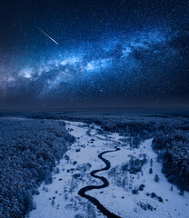 Wall Mural - milky way over frozen river and snowy forest in winter.