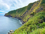 Fototapeta Mosty linowy / wiszący - Green coastal cliffs touching the blue ocean in Sao Miguel island, Azores.