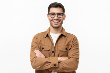 Wall Mural - Portrait of young happy laughing man wearing brown shirt and eyeglasses, holding arms crossed, isolated on gray background