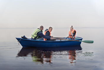 Man, boy and girl in boat on oars in life jackets