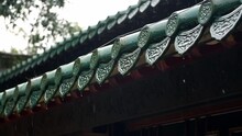 Raindrops fall from the eaves of an ancient building in slow motion