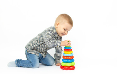 Small baby boy is playing with colourfull pyramide isolated on white background. Education and learn game concept with copy space.