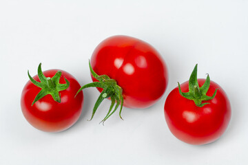 Wall Mural - Three red fresh tomatoes on a light background. View from above. Vegetarian food concept.