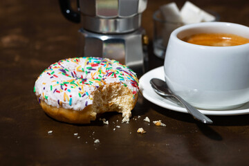 Wall Mural - sweet donut with white frosting and cup of fresh coffee on dark wooden background