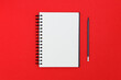 Blank spiral notebook and pencil on red background. Top view with copy space for input the text.