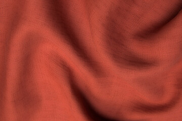 Close-up texture of natural red or pink fabric or cloth in same color. Fabric texture of natural cotton, silk or wool, or linen textile material. Red and orange canvas background.