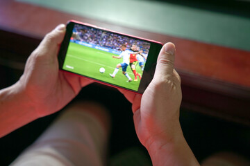 man watching football and sport stream on mobile phone. close up view. home entertainment concept.