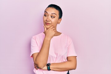 Sticker - Beautiful hispanic woman with short hair wearing casual pink t shirt with hand on chin thinking about question, pensive expression. smiling with thoughtful face. doubt concept.