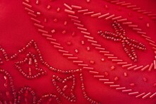 Red Beaded Fabric. Closeup Of Hand-made Textile Clothing Decoration And Bead Embroidery. Fancy Pattern Used For Clothing Design, Beautiful Fashion Apparel, And Luxury Attire Detail.